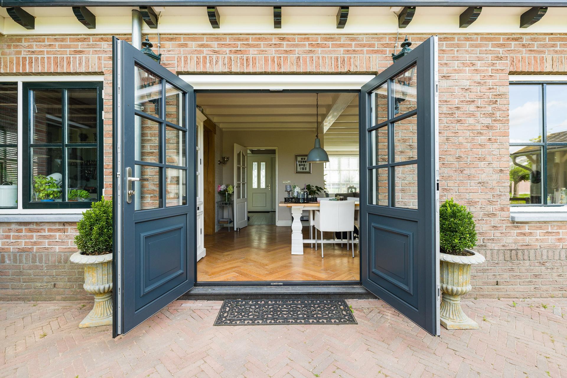 Moderne witte kunststof kozijnen in een rode bakstenen gevel van een woning.