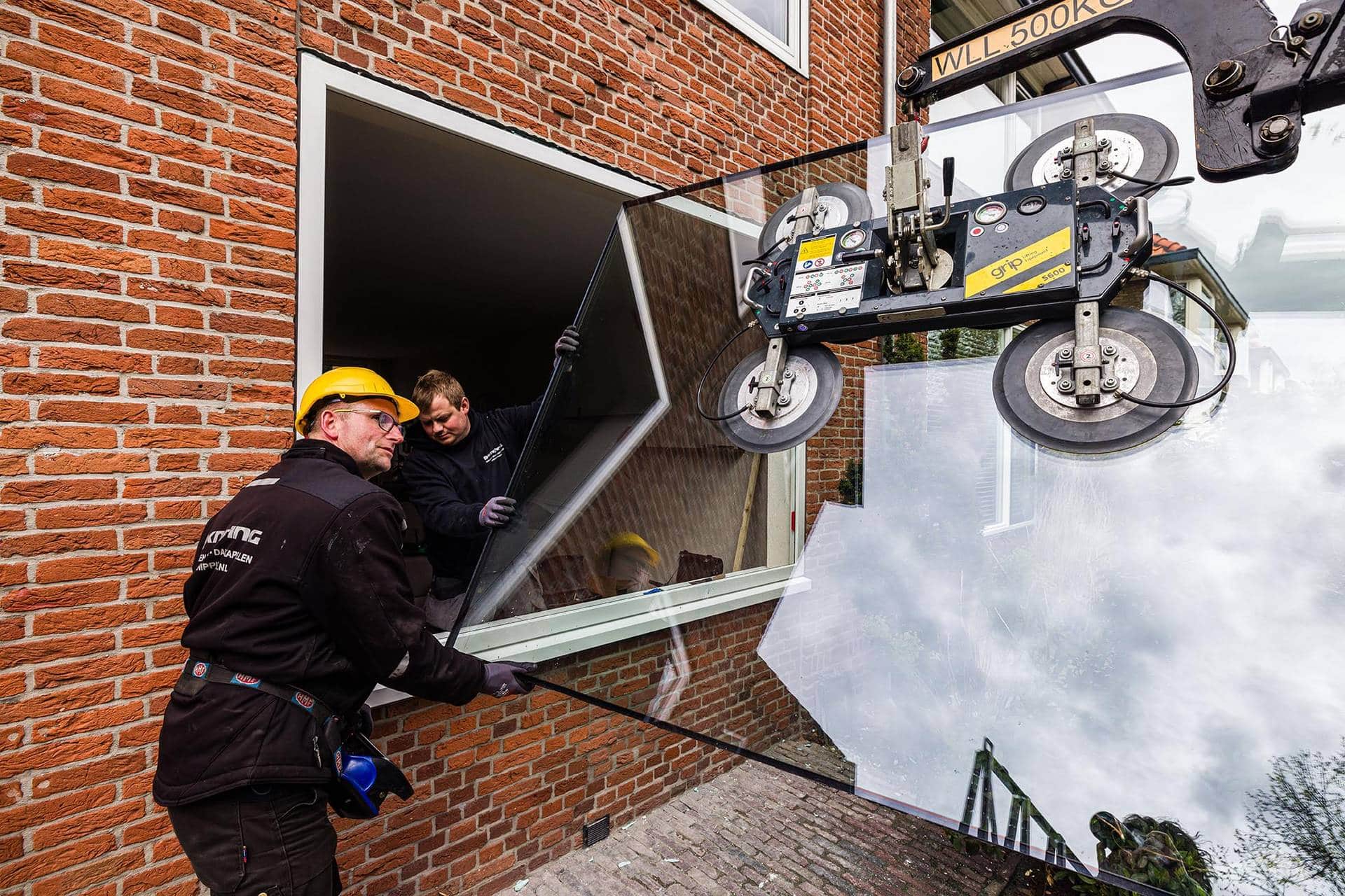 Werknemer installeert isolerend glas in een raamkozijn op een zonnige dag.