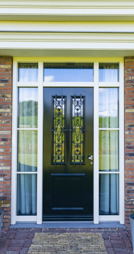 Moderne woning met rode bakstenen gevel en grote ramen, omgeven door een verzorgde tuin.